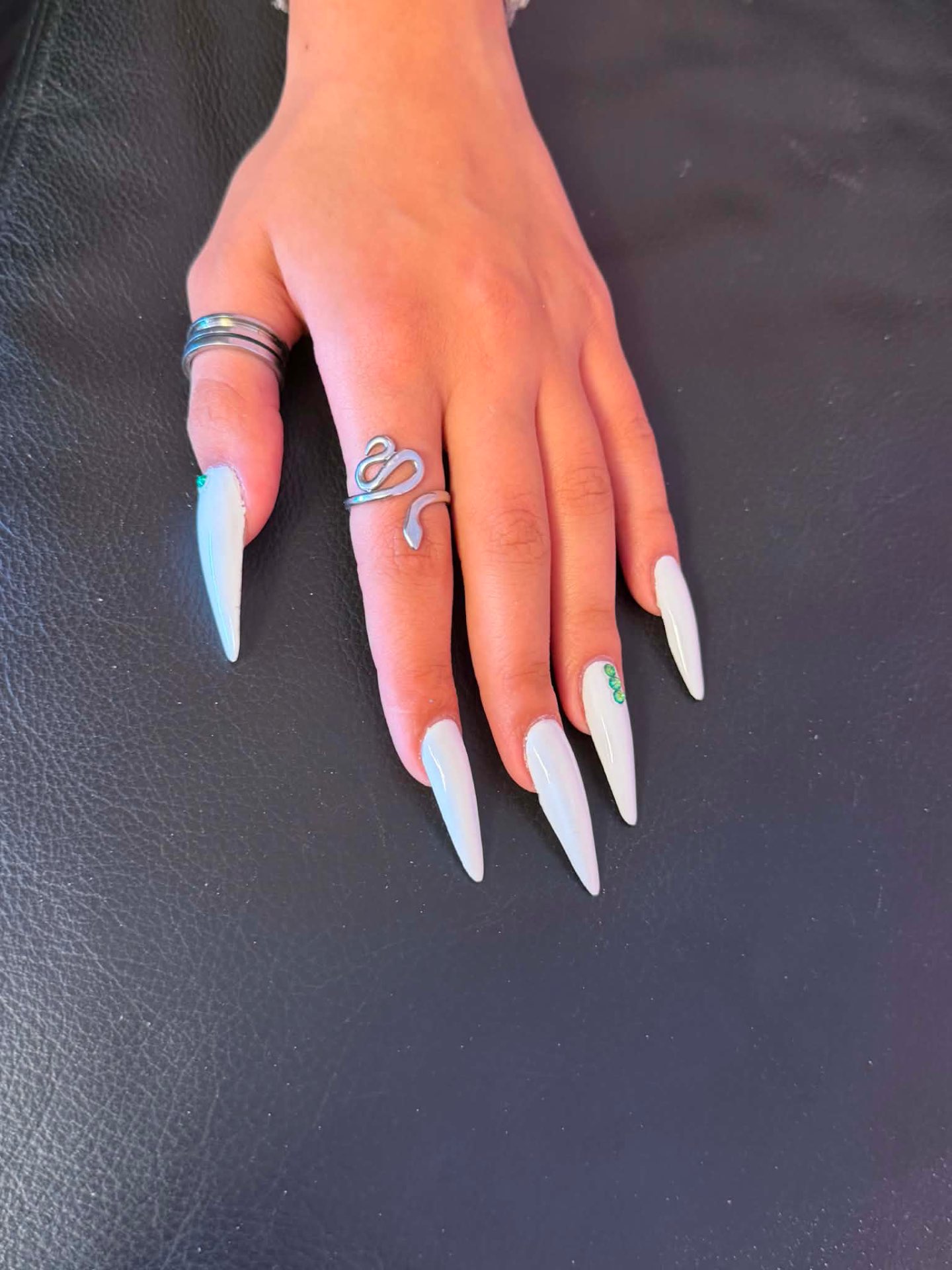 White stiletto nails with green gem accent