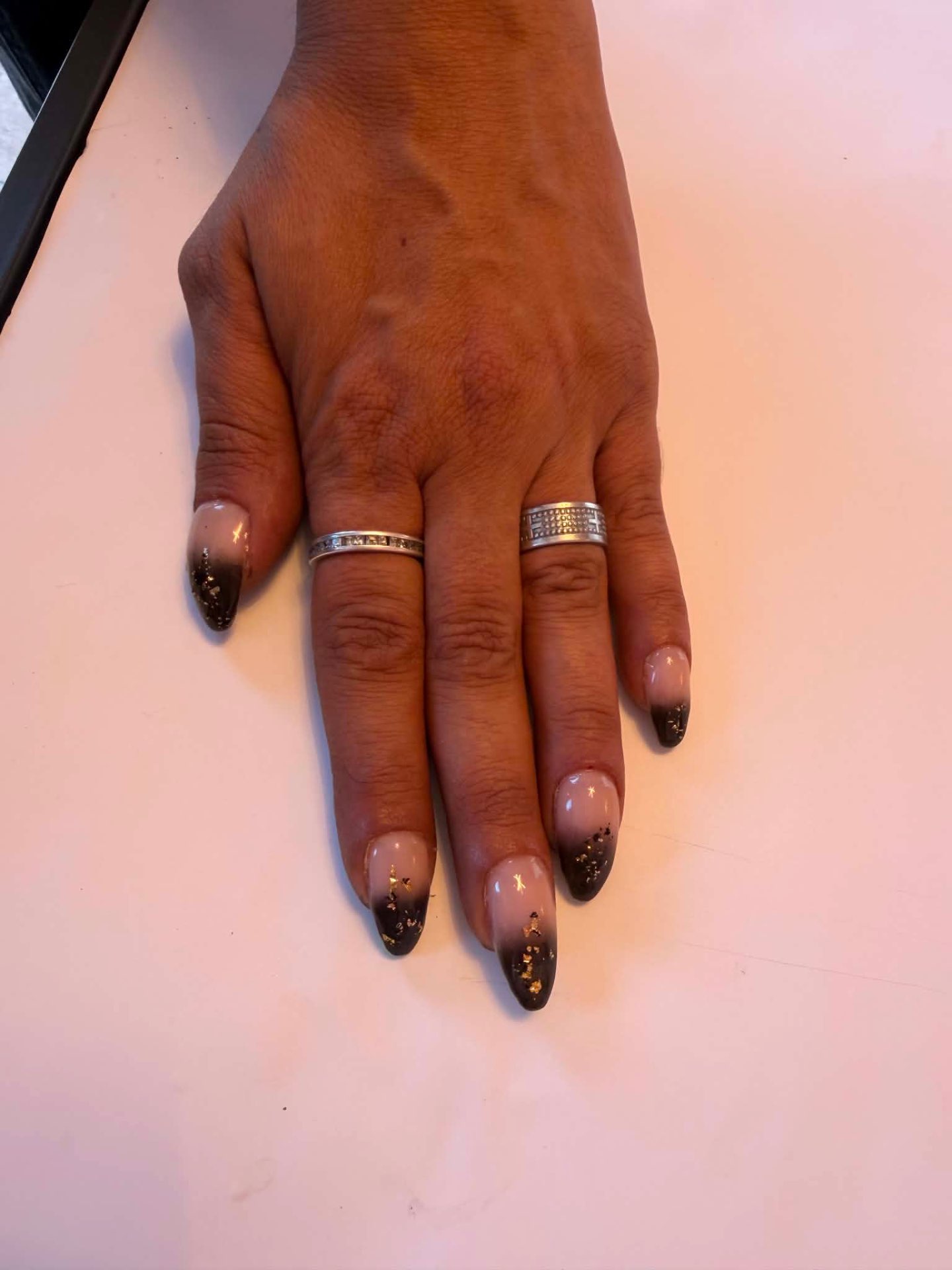 Nude nails with dark brown tips and gold flakes